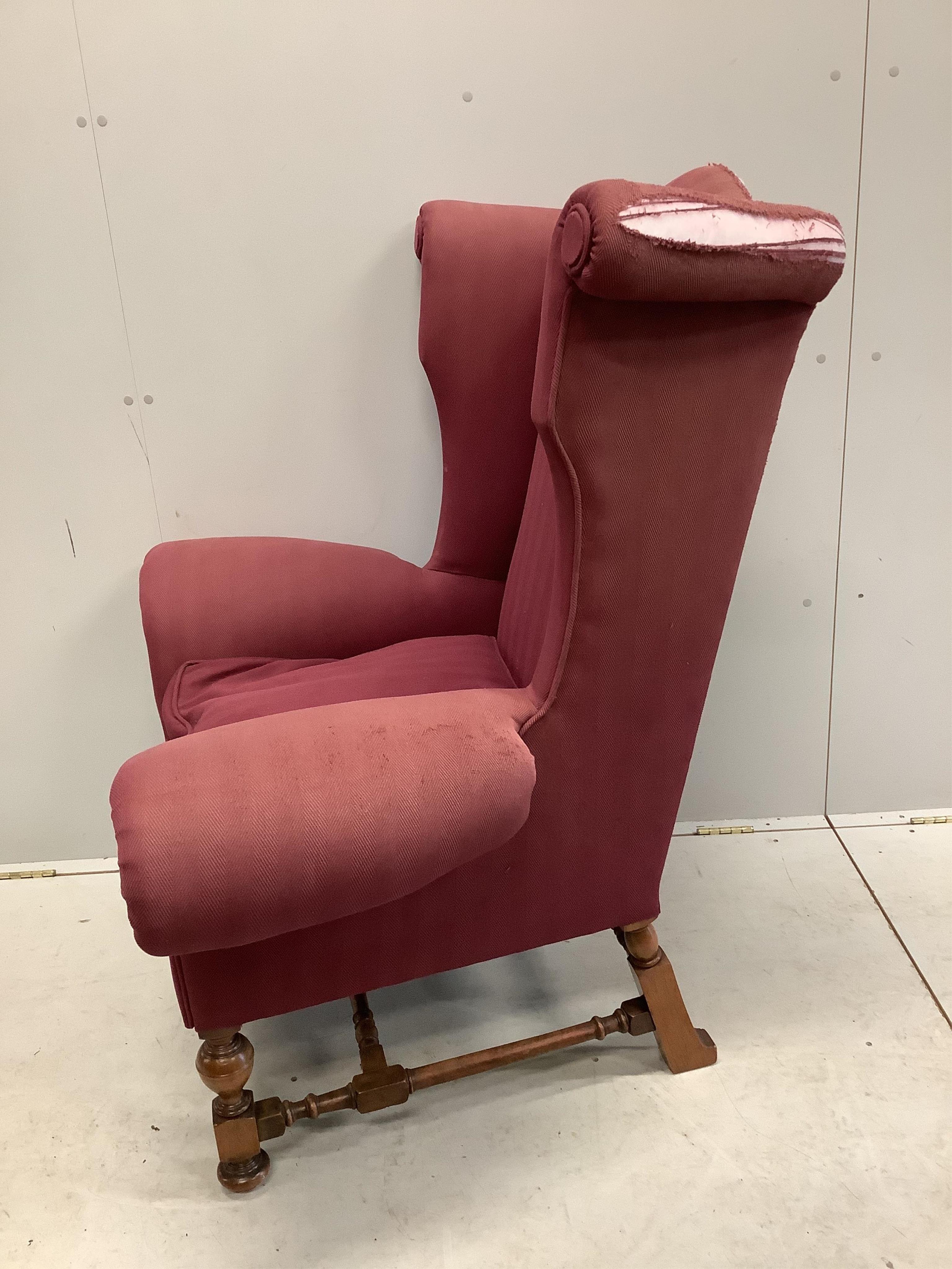 A Queen Anne revival wing armchair with wide scroll arms on turned walnut underframe, width 106cm, depth 70cm, height 120cm. Condition - fair, upholstery poor